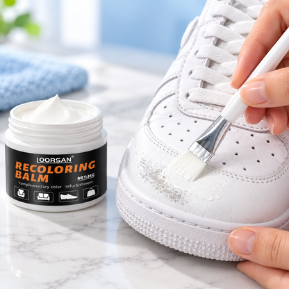 Applying white shoe recoloring balm to a scuffed leather sneaker